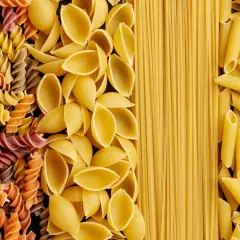 Różne rodzaje makaronu: kolorowe fusilli, muszelki, spaghetti i penne. Wybór wpływa na indeks glikemiczny posiłku.