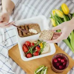 Zdrowy posiłek: pełnoziarniste pieczywo, hummus, pomidorki, kiwi i dżem z owoców leśnych. Idealne, by dowiedzieć się, co jeść przy zaparciach.
