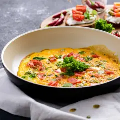 Omlet z pomidorami i ziołami na patelni. Idealny sposób, jak ograniczyć węglowodany w diecie.