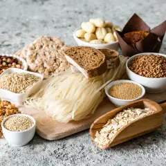 Różnorodne produkty zbożowe i strączkowe: ryż, kasza, makaron, chleb, płatki owsiane, fasola.