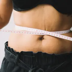 Kobieta mierzy talię centymetrem. Czy to początek drogi, jak szybko schudnąć 20 kg?