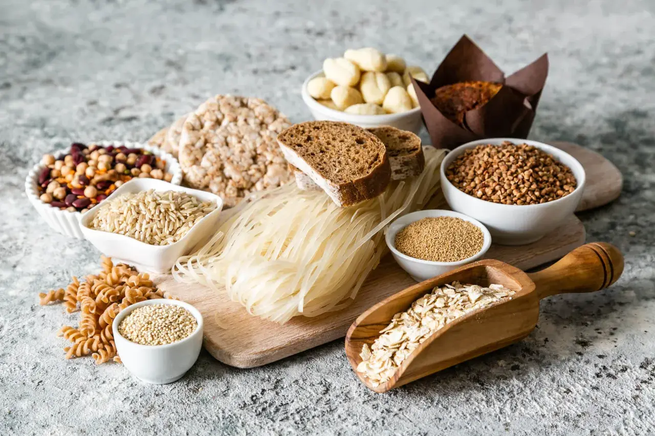 Różnorodne produkty zbożowe i strączkowe: ryż, kasza, makaron, chleb, płatki owsiane, fasola.