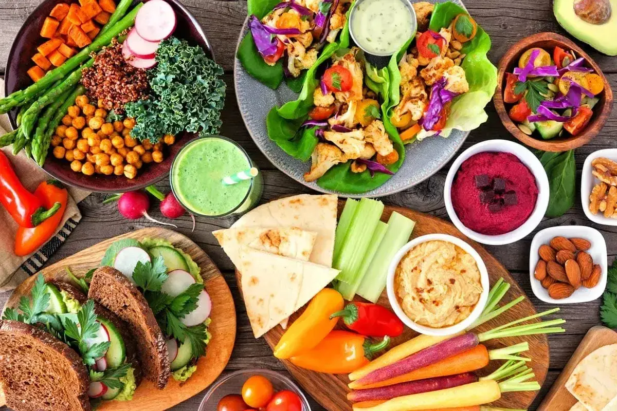 Kolorowe, wegańskie potrawy: sałatki, wrapy, hummus, smoothie i pieczywo. To pokazuje, co to jest weganizm – dieta roślinna pełna smaków i zdrowia.