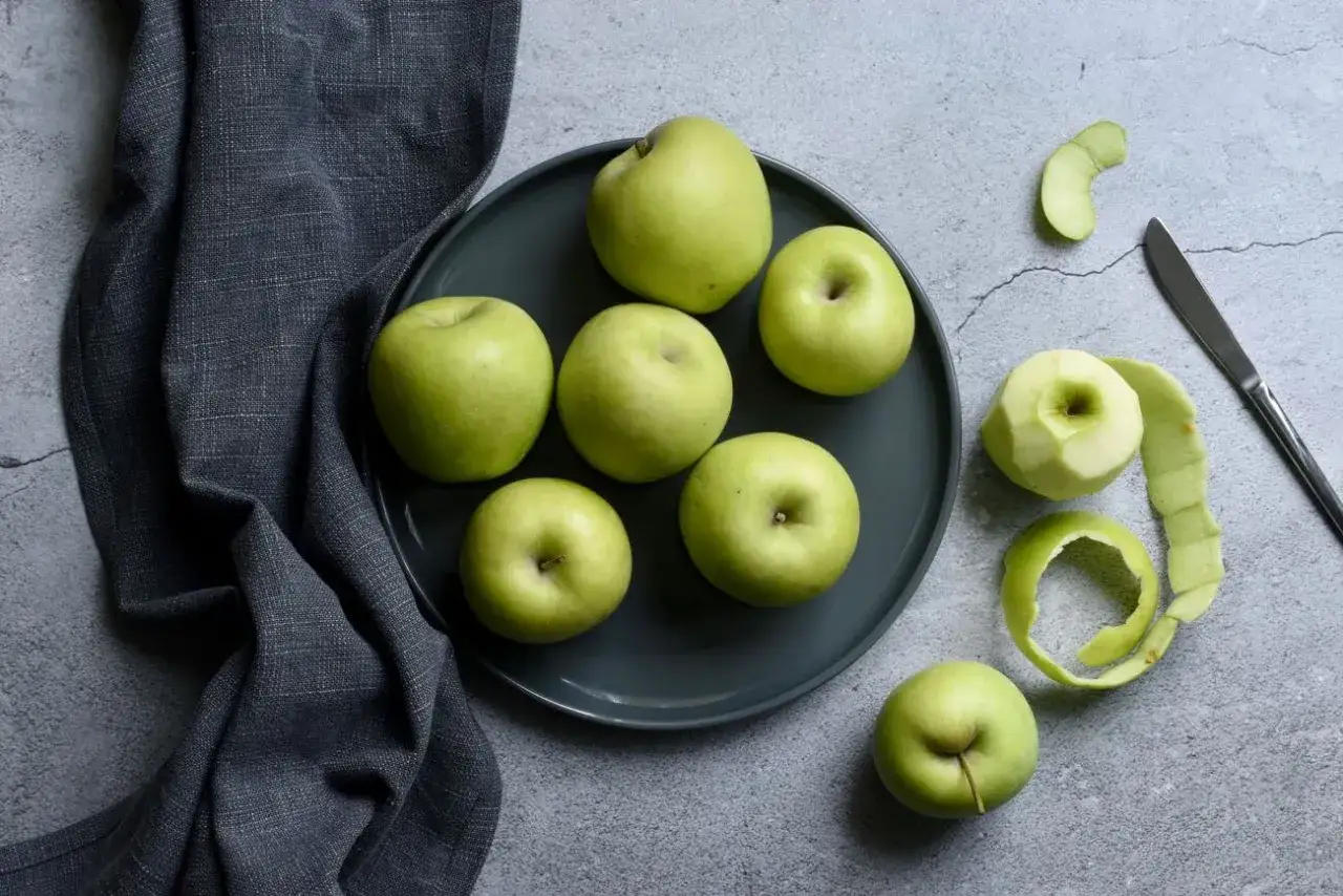 Zielone jabłka na talerzu i obok obierki. Idealne na dietę 500 kcal.